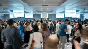 A room full of people at a conference, standing and wandering around