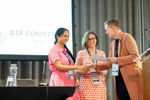 An award winner being presented with a certificate on stage