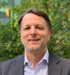 Eric Anvar smiling in front of a tree.